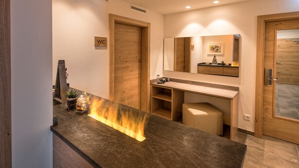 Un baño moderno con tocador de madera, un espejo y un letrero que indica el inodoro.