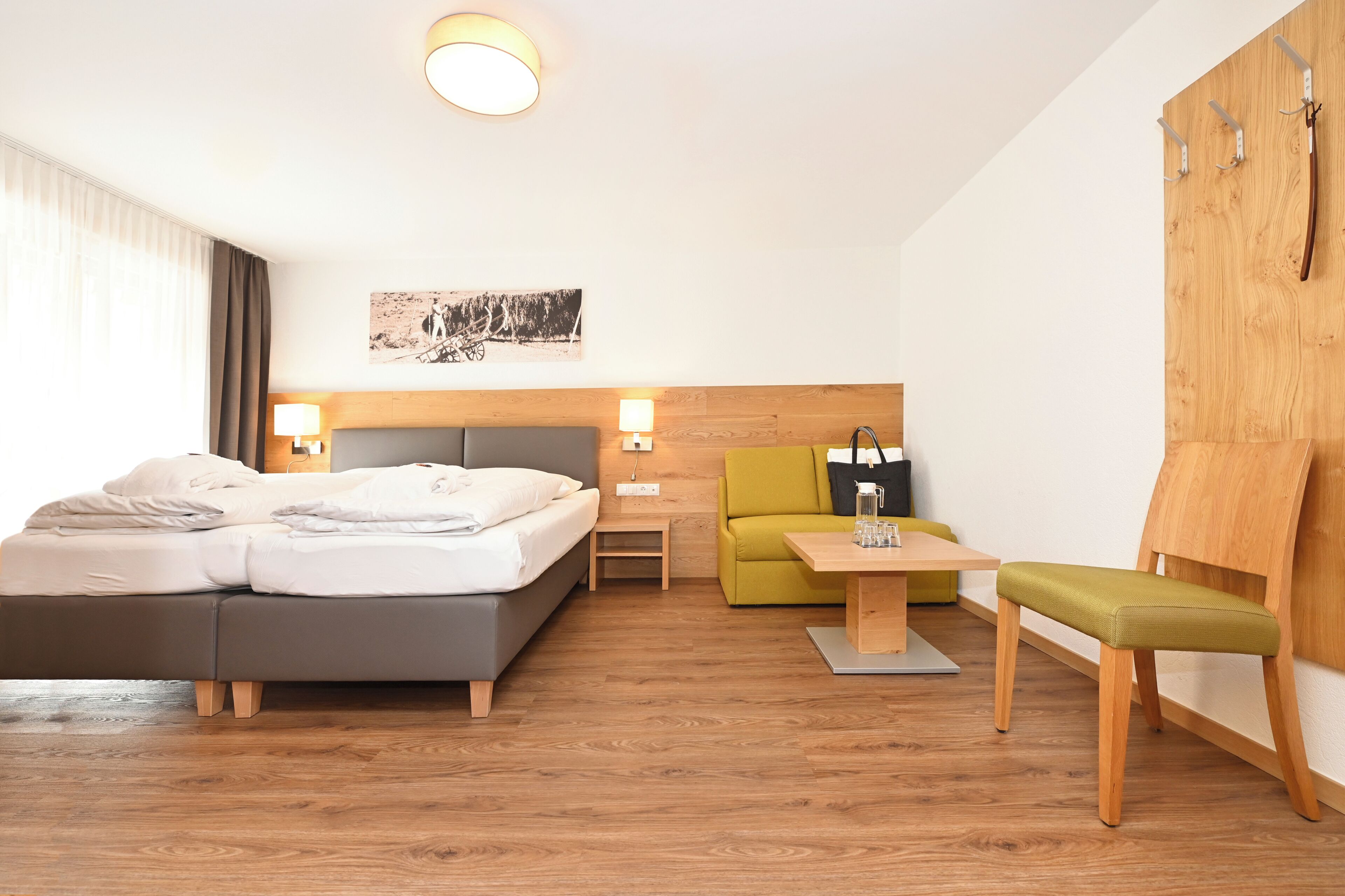 Ein Hotelzimmer mit einem Bett, einem kleinen Tisch, einem Sessel, einer Couch und einem Holzschrank.