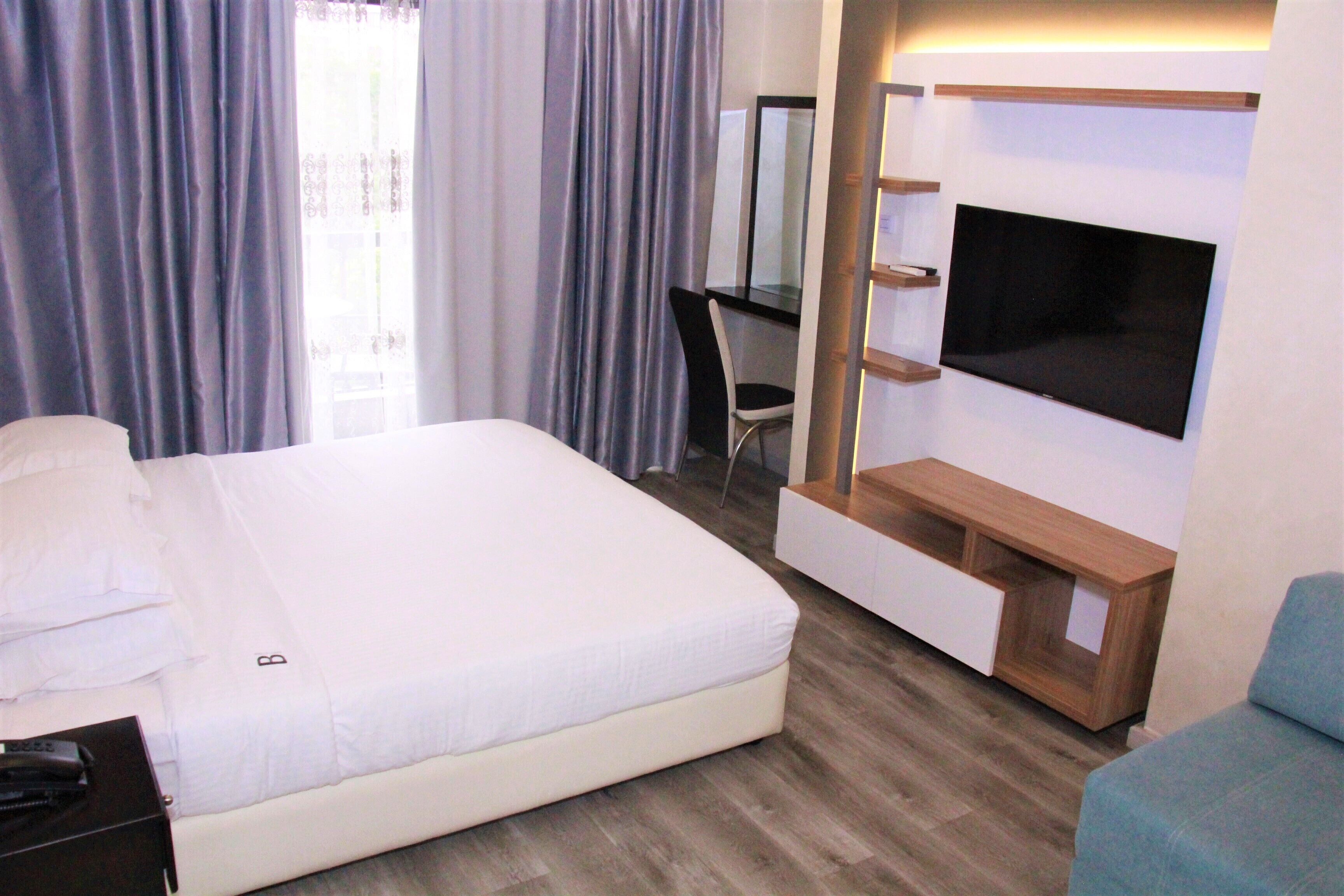 A hotel room with a bed, a desk, a TV, and a chair.