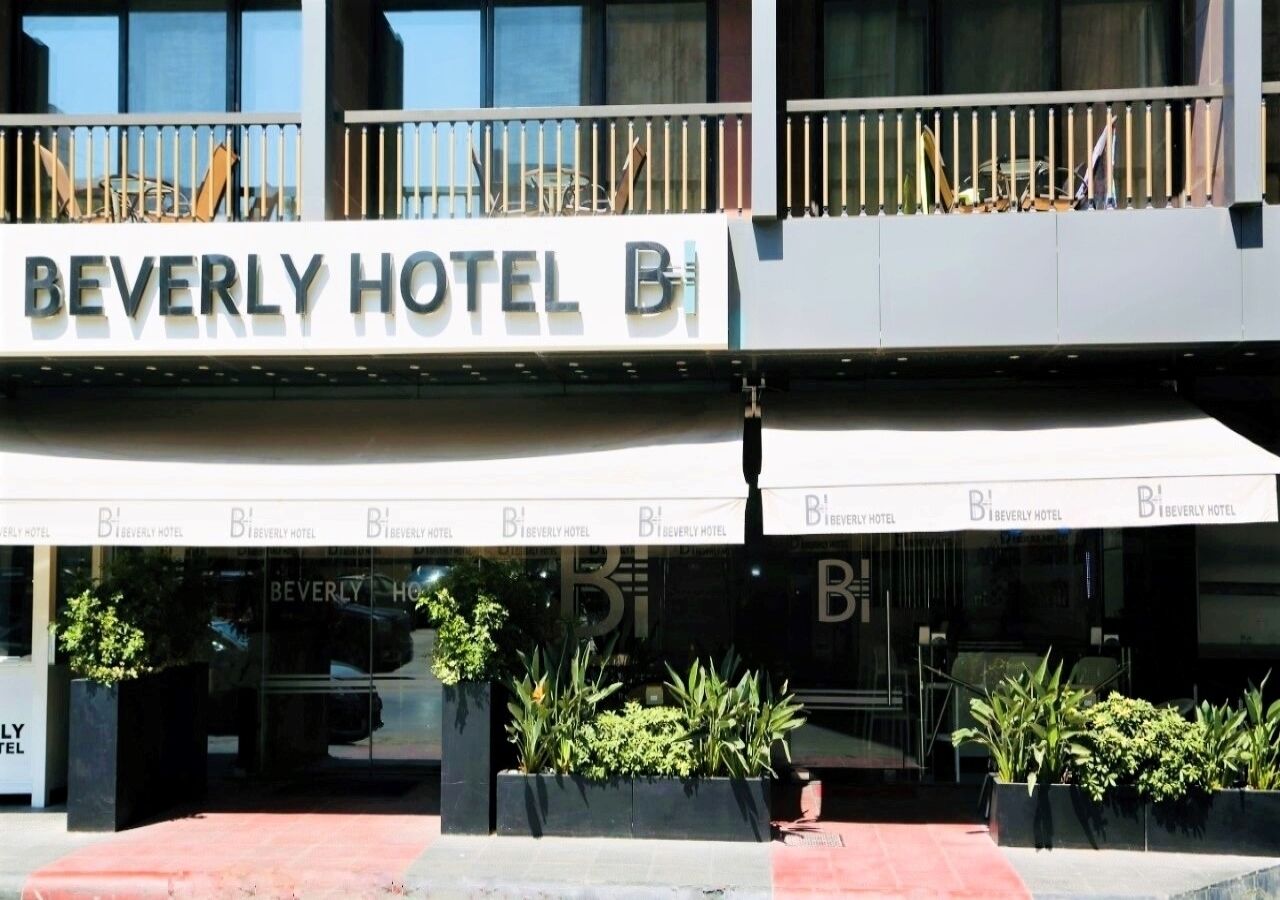 Het exterieur van het Beverly Hotel, met een moderne gevel, grote ramen en een opvallend bord.