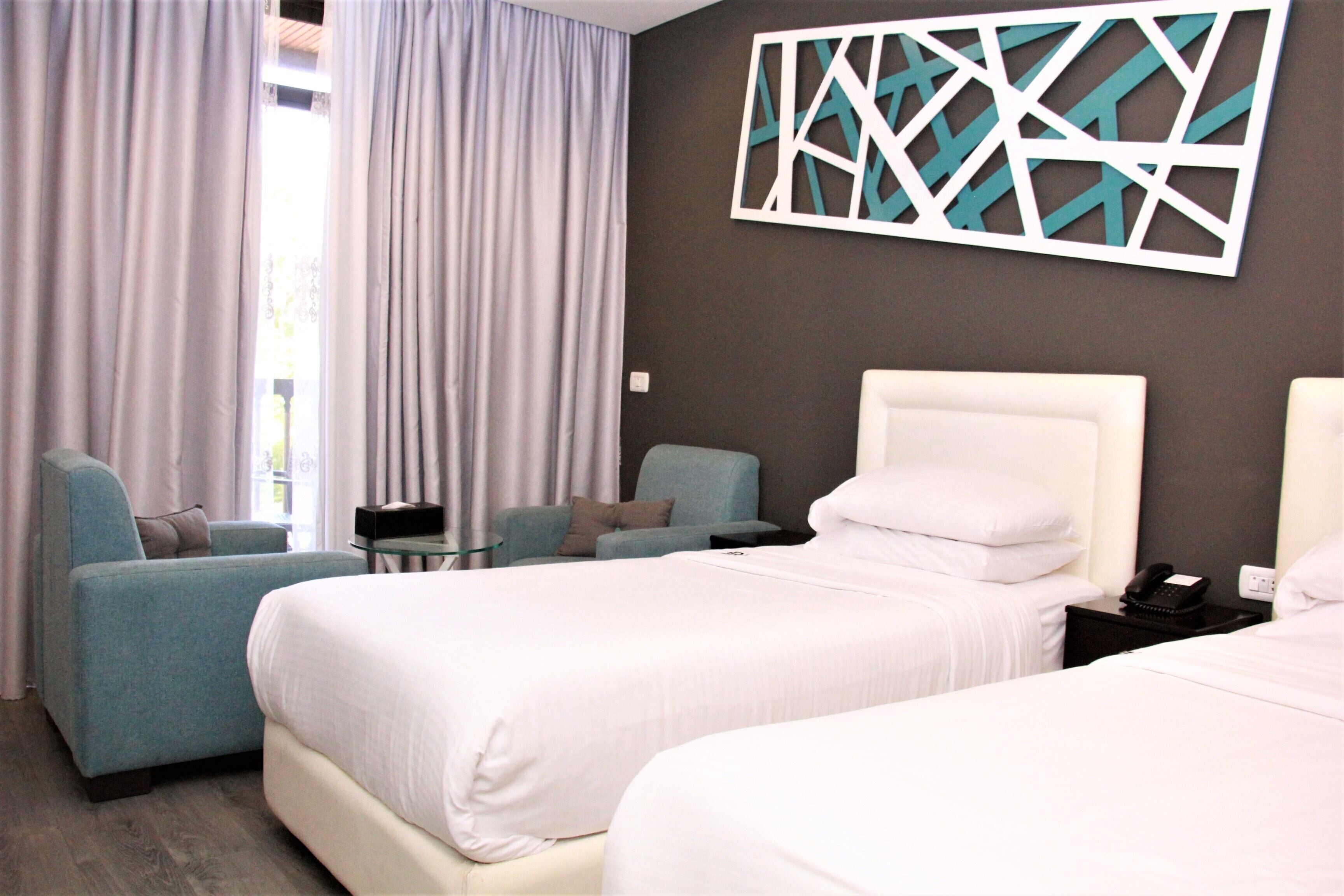 Een hotelkamer met twee bedden, een bank, een tafeltje en een decoratief wandobject.