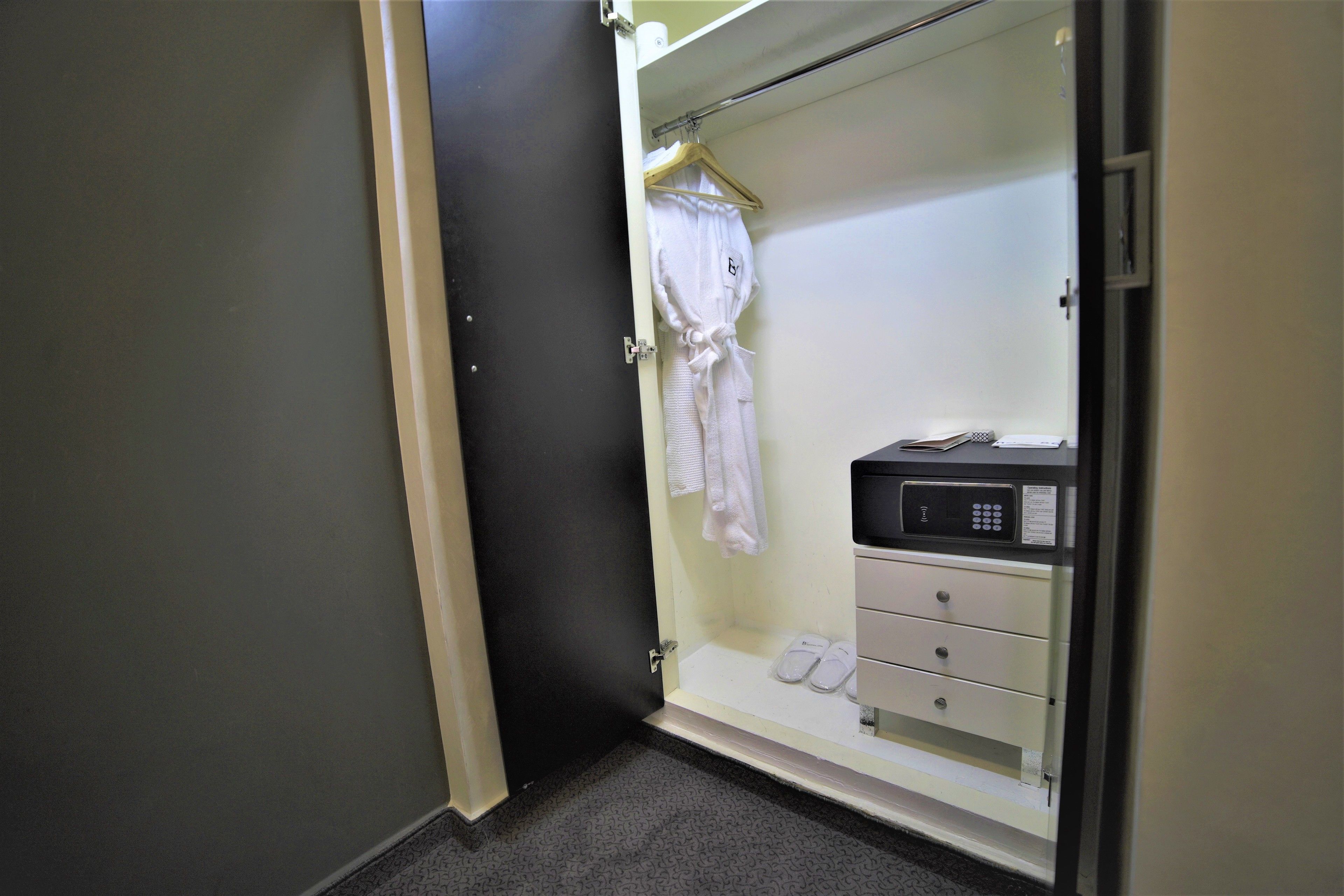 A walk-in closet with a hanging robe, a shoe rack, and a storage unit with drawers.