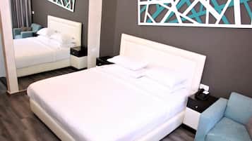 A hotel room with a large bed, a nightstand, a chair, and decorative wall art.