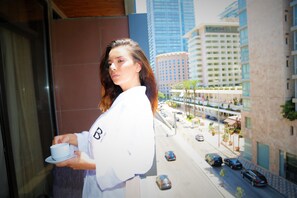 A person holding a cup, standing in front of a building with a view of a street and other buildings. - Beverly Hotel Beirut (Beirut)