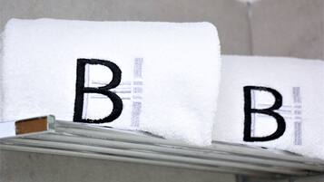 A white towel with the letter "B" embroidered on it, hanging on a metal rack.