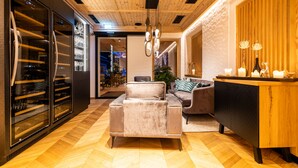 Una sala de estar moderna con techo de madera, un refrigerador de vidrio para vino, un sofá gris y un aparador de madera.