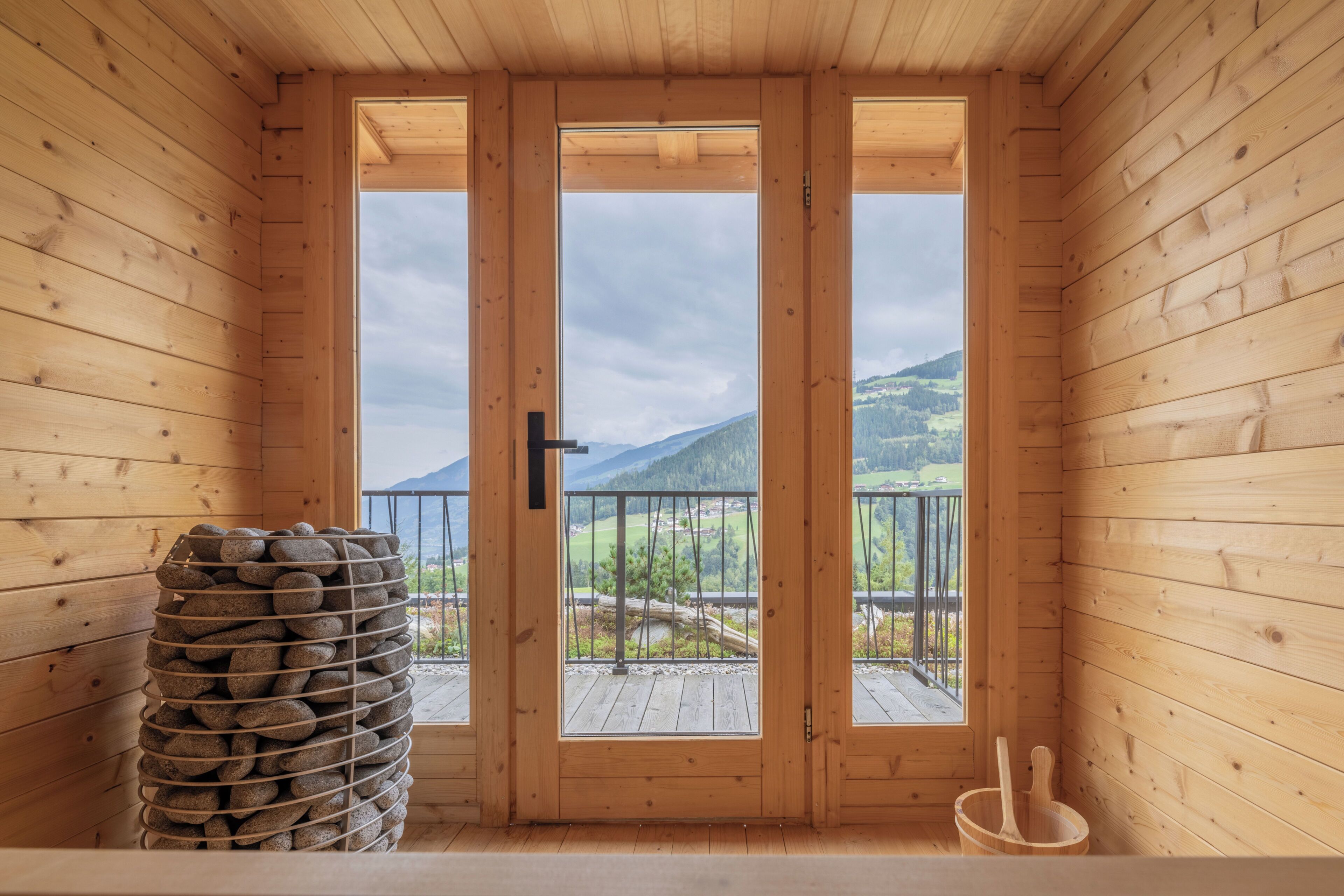 Une cabane en bois dotée d’un balcon, d’un mur en pierre et d’un seau en bois.