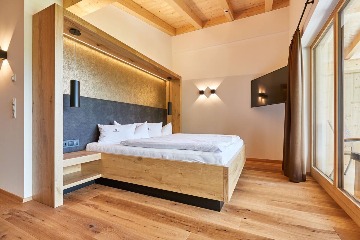 A modern bedroom with a wooden bed, built-in shelves, and a large window with curtains.