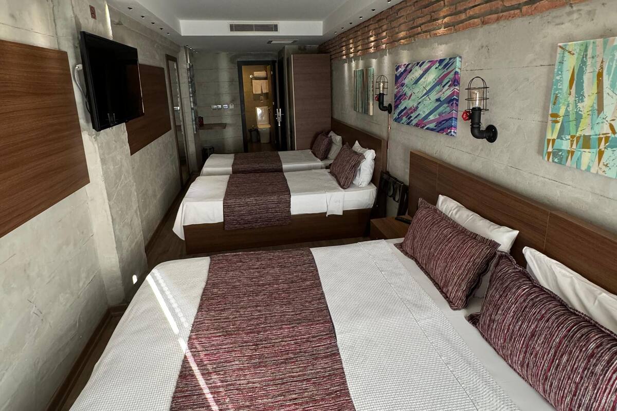 A hotel room with two beds, a TV, artwork on the walls, and a brick accent wall.