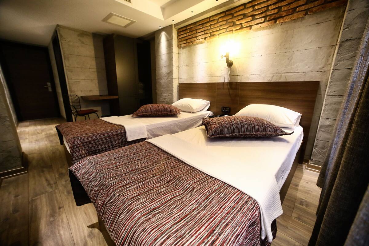 A hotel room with two beds, a brick accent wall, and a small seating area.