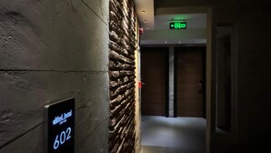 A hallway with a stone wall, a digital sign indicating room number 602, and an exit sign.
