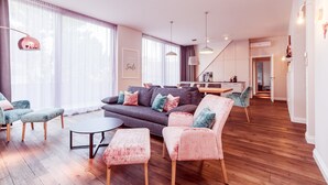 Ein modernes Wohnzimmer mit einer Couch, Sesseln und einem Essbereich.