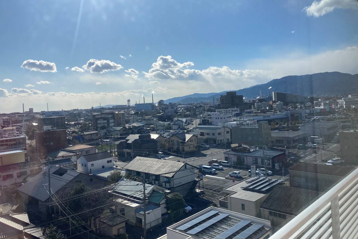 Un paisaje urbano con diversos edificios, incluyendo residenciales y comerciales, bajo un cielo despejado con nubes dispersas.