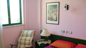 Une pièce comprenant un lit, une chaise, une lampe et un tableau accroché au mur.