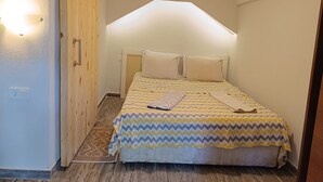 Une petite chambre à coucher, chaleureuse et accueillante, avec un lit, une armoire en bois et un luminaire au plafond.