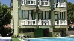 Un immeuble à plusieurs étages doté d’un espace piscine, avec des balcons pourvus de rampes blanches et une piscine à l’eau d’un bleu limpide.