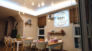 A cozy dining area with a table set for two, a ceiling light fixture, and a sign indicating a cafe and restaurant.