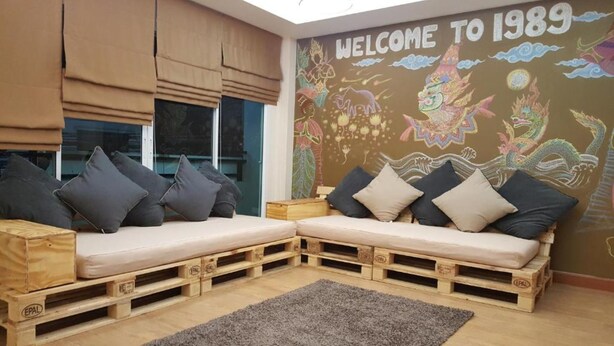 A room with a sofa set made of wooden pallets, a grey rug, and a mural on the wall.