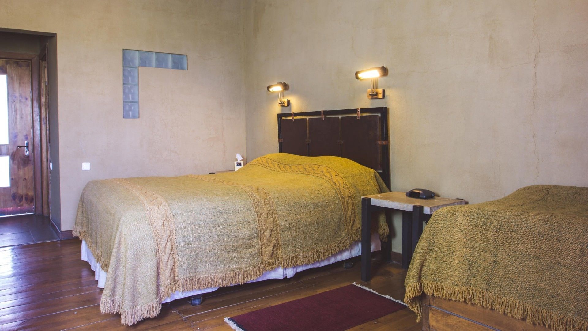 A room with a bed, a desk, and a chair, all covered with a textured blanket.