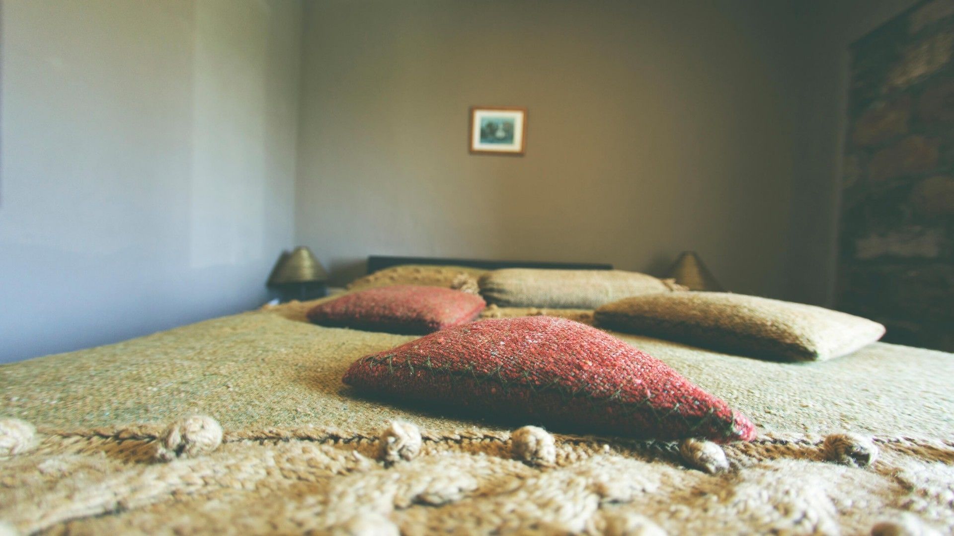 A room with a bed, pillows, and a small framed picture on the wall.