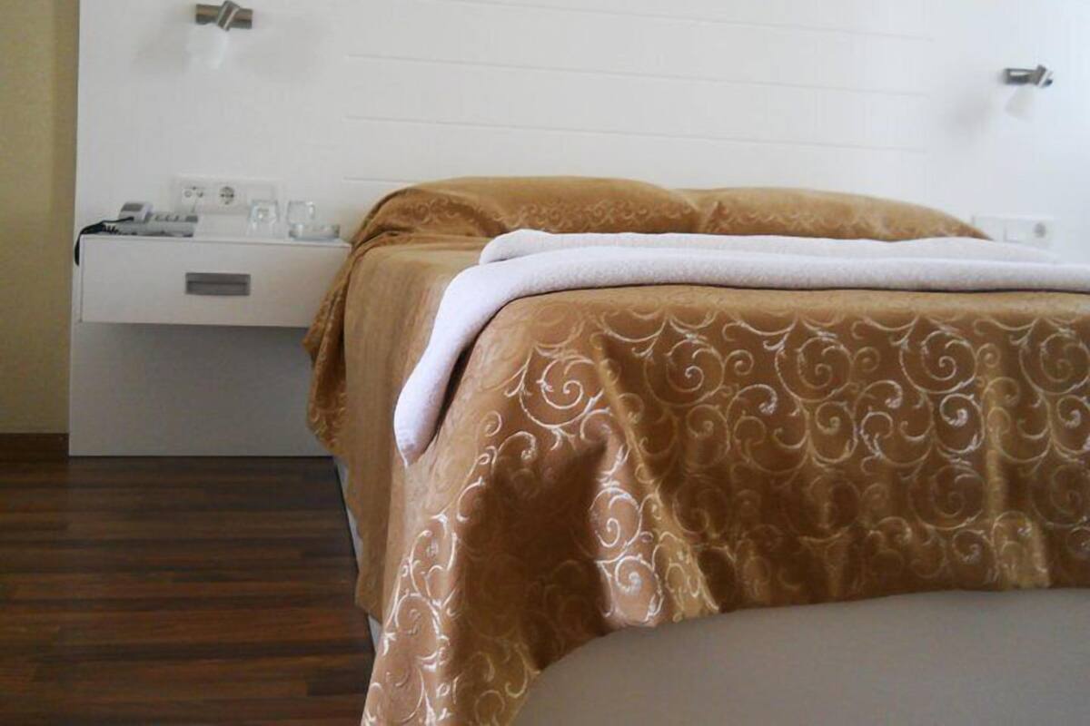 Una habitación de hotel con una cama, una mesita de noche y un enchufe en la pared.