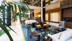 A spacious lobby with a high ceiling, modern seating arrangements, and a large potted plant. - Dedeman Cizre (Cizre)