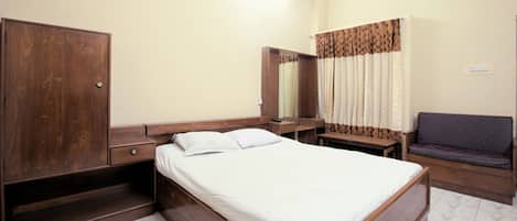 Una habitación de hotel con cama, un armario de madera, un escritorio, una silla y un baño con cortina de ducha.