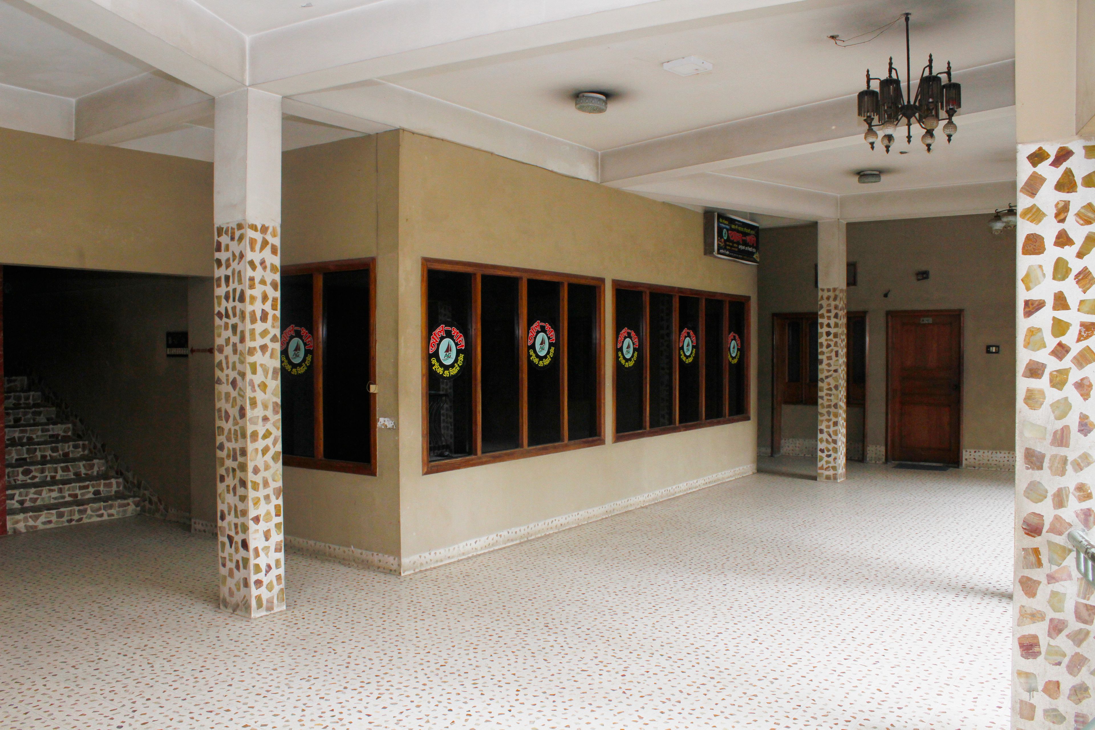 Un hall d’entrée spacieux, doté d’un sol carrelé, d’un lustre et d’une rangée de fenêtres ornées de vitraux décoratifs.