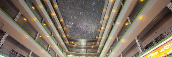 Un atrio de varios niveles con techo que simula un cielo estrellado y múltiples balcones.