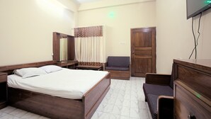 Een hotelkamer met een bed, een bureau, een stoel, een kledingkast en een televisie.