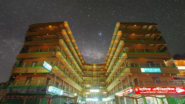 Een hotel met meerdere verdiepingen, een centraal atrium, balkons en diverse borden.