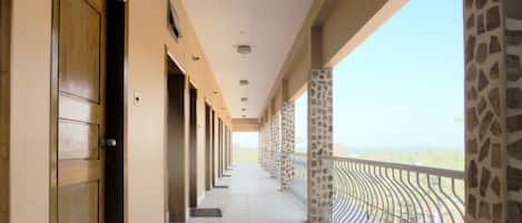 A corridor with doors, a tiled floor, and a railing overlooking a scenic view.