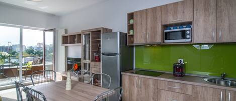 Une cuisine moderne avec des meubles en bois, un réfrigérateur en acier inoxydable, un four à micro-ondes et un revêtement mural vert.