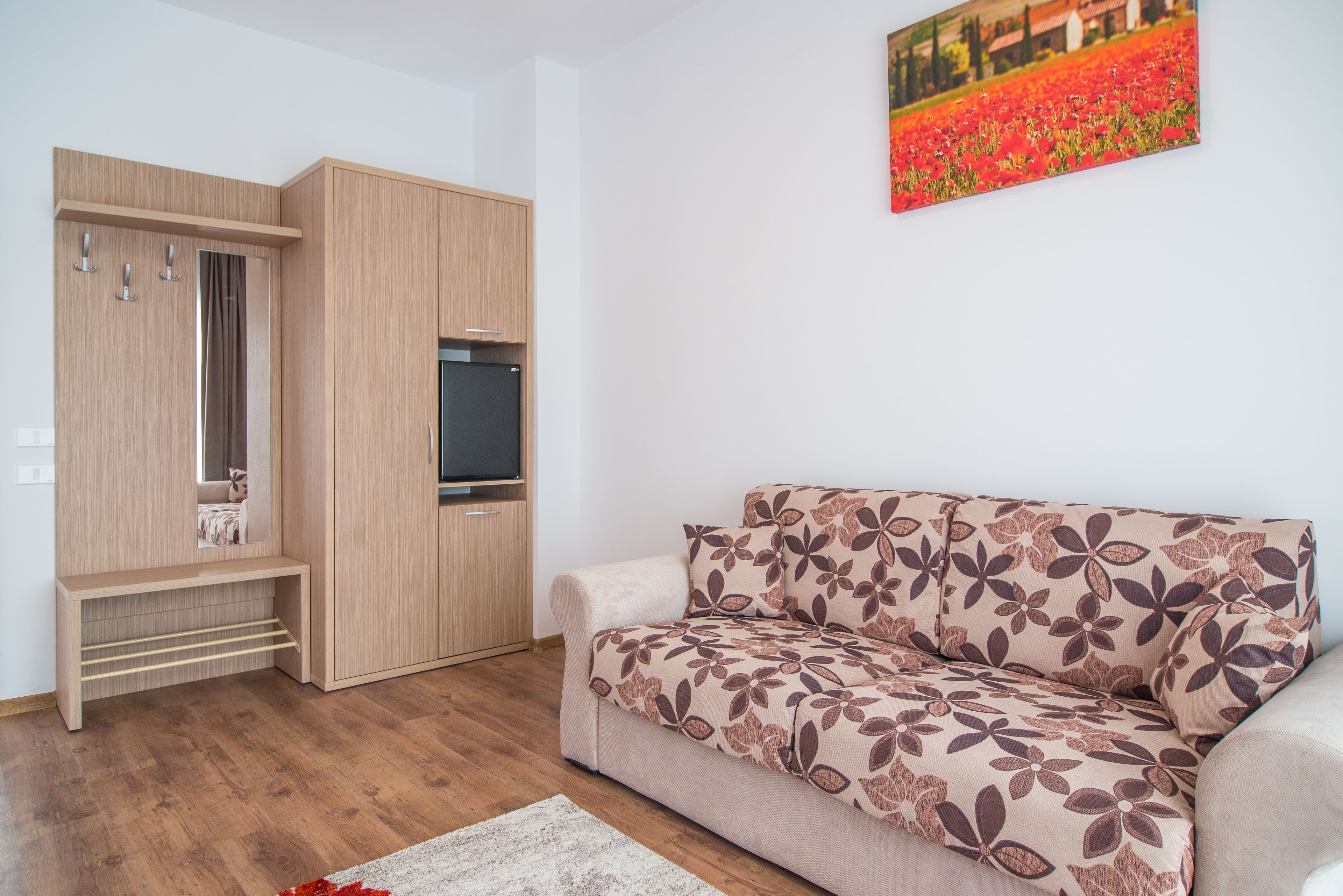 Una sala de estar con un sofá, un mueble de madera y un televisor de pantalla plana.