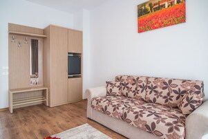 Una sala de estar con un sofá, un mueble de madera y un televisor de pantalla plana.