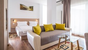 A modern hotel room with a bed, sofa, and glass coffee table.
