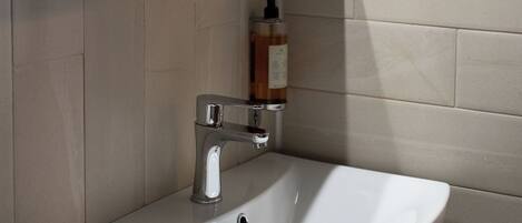 A bathroom with a white sink, a mirror, a towel, and a hairdryer mounted on the wall.