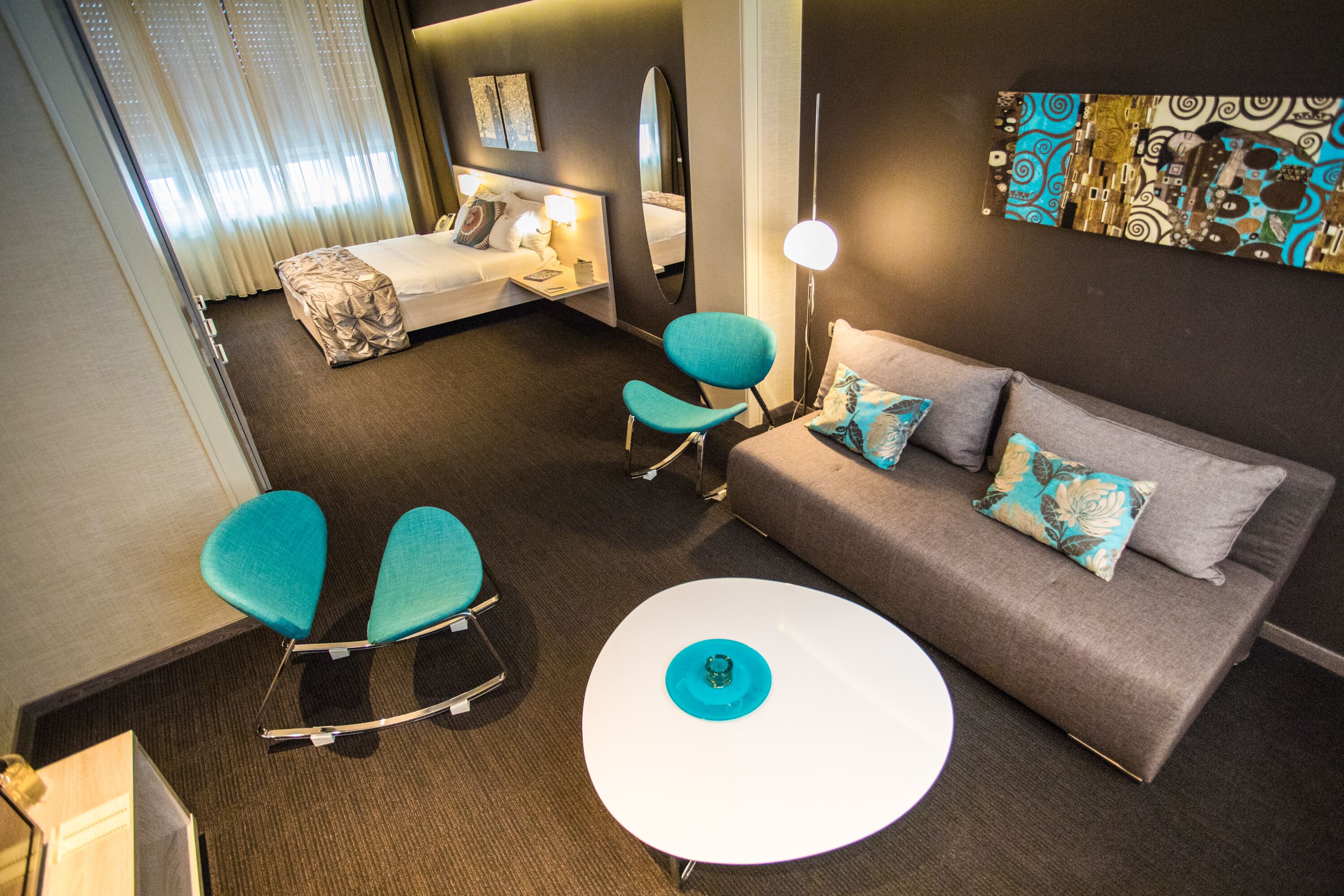 A hotel room with a bed, a sofa, a small round table, and two chairs.