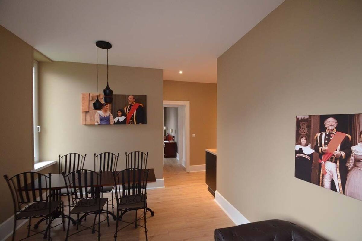 A dining area with a table and chairs, a hanging light fixture, and a framed picture on the wall.