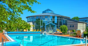 A modern hotel with a large swimming pool, a covered outdoor area, and a distinctive blue-roofed structure. - Kurhotel Bad Rodach (Bad Rodach)