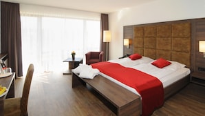 A hotel room with a large bed, a desk, and a chair.