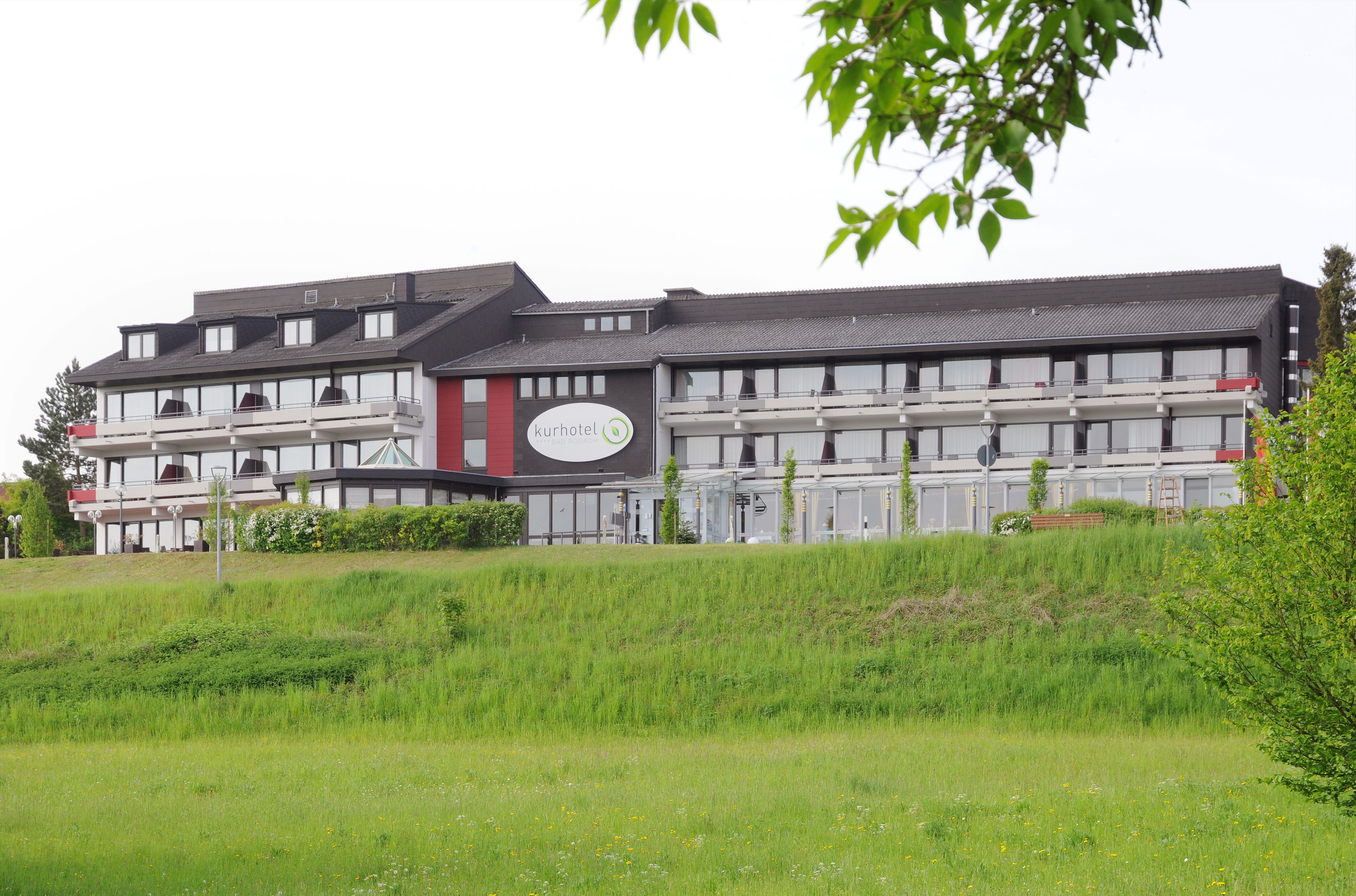 A modern kurhotel building with multiple balconies and a sign.