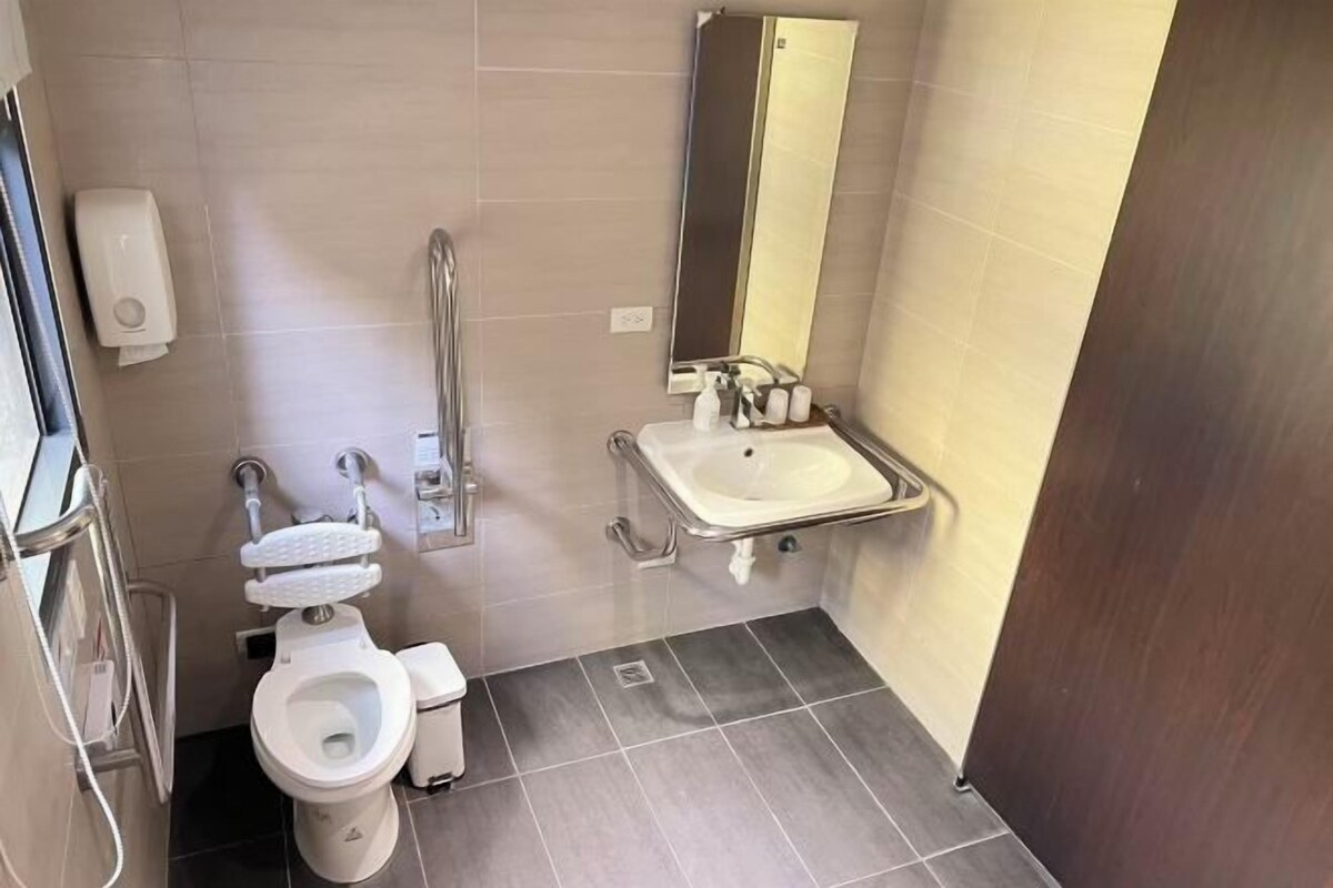 Un baño moderno con inodoro, secamanos y lavabo.