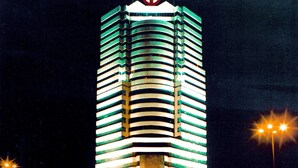 A tall hotel with a distinctive circular logo on the top, featuring horizontal stripes and a central light fixture. - ZhongYin Jasper Hotel Baoding (Baoding)