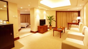 A hotel room with a bed, a TV, a desk with a lamp, a sofa, and a potted plant. - ZhongYin Jasper Hotel Baoding (Baoding)