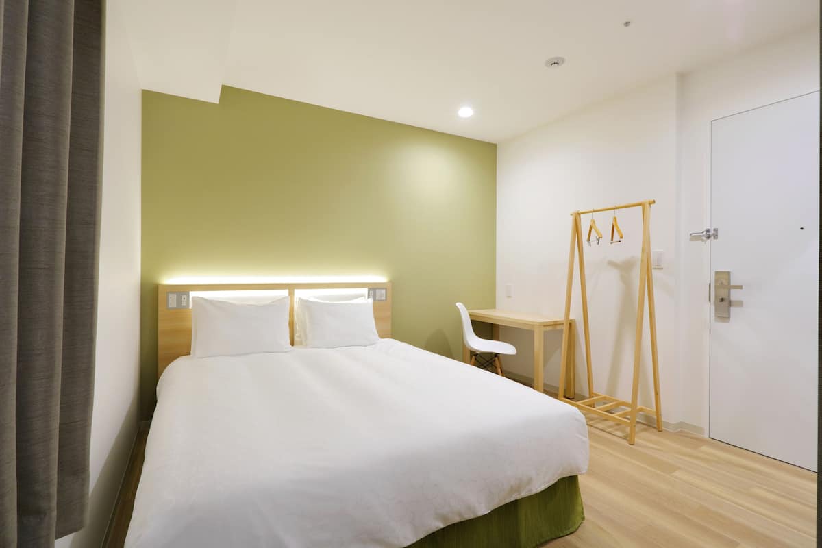 A hotel room with a bed, a desk, and a chair.