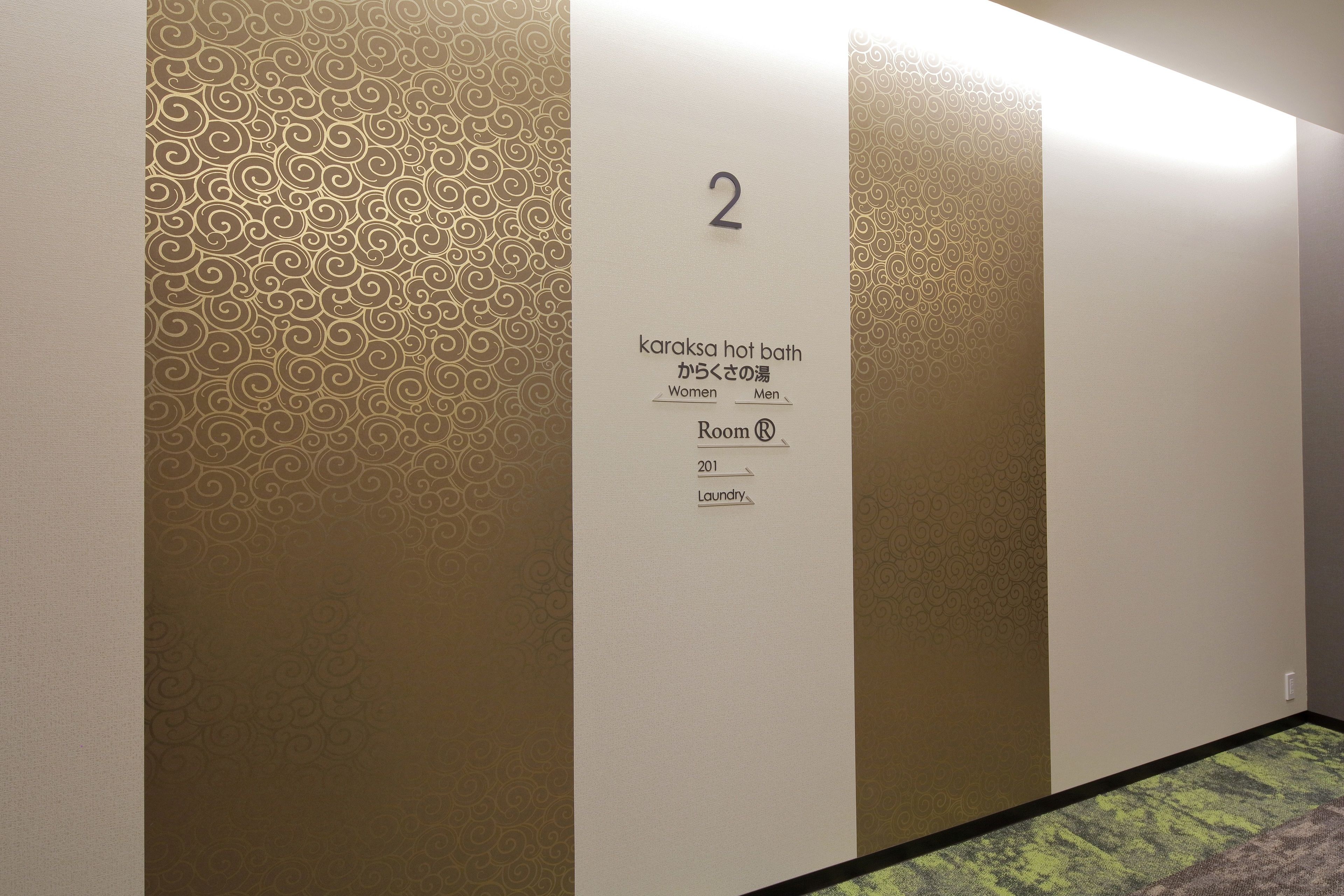 Habitación de hotel con un cartel con el número 2, indicando el número de la habitación. La habitación se identifica como 'karaksa hot bath' para mujeres y hombres, sugiriendo que tiene una sauna. El número de habitación es 201 y está designada para uso de lavandería.