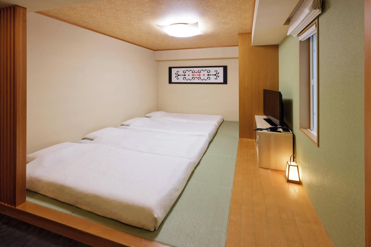 A room with a bed, a bedside table, a TV, and a framed picture on the wall.