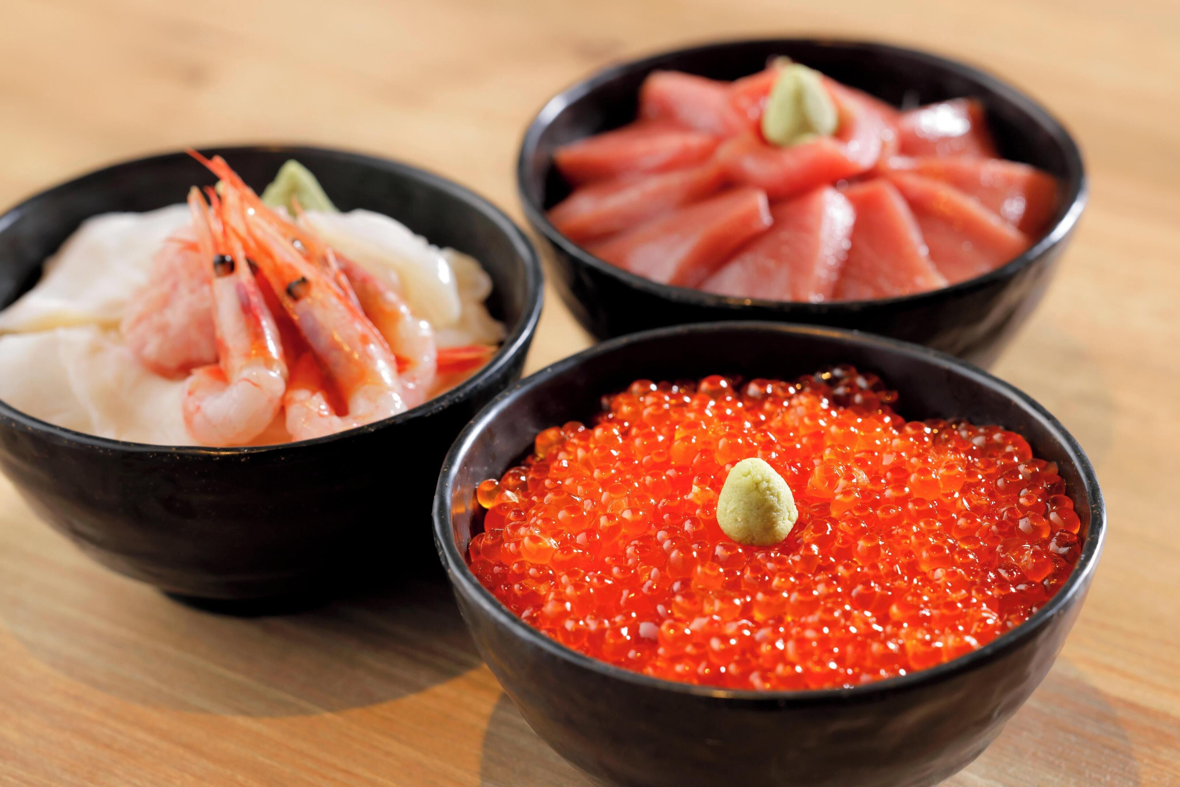 Three bowls of food on a wooden table.