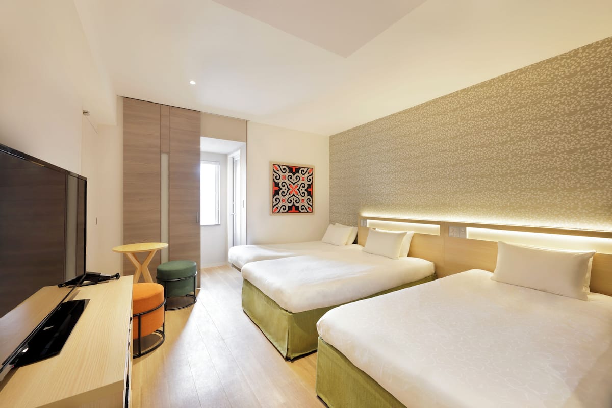 A hotel room with two beds, a desk, a TV, and a small table.